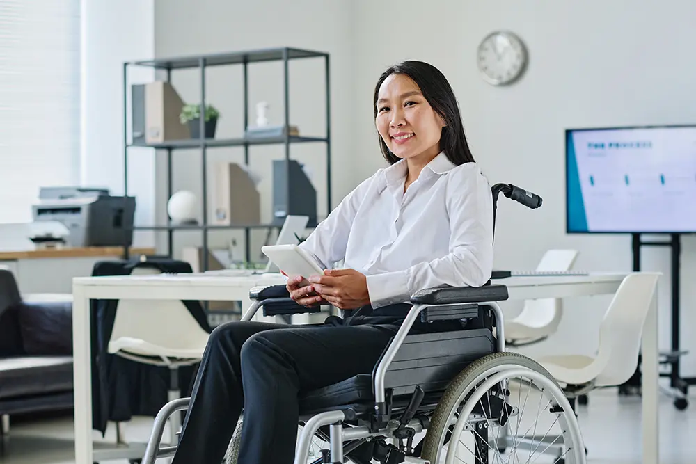 Woman in a wheelchair working in an office, representing global accessibility and digital inclusion